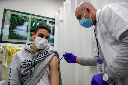 Un trabajador de la salud administra una dosis de la vacuna Pfizer-BioNtech a un hombre en los Servicios de Salud de Clalit, en el barrio palestino de Beit Hanina, en el este de Jerusalén