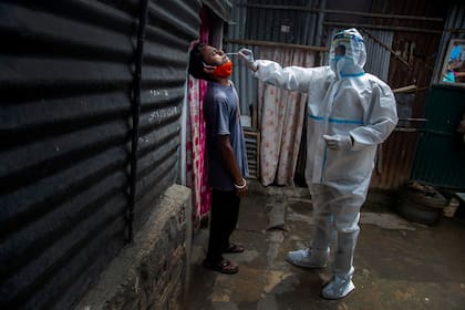 Un trabajador de la salud, con un traje de protección, toma una muestra nasal a un hombre para una prueba de Covid-19 en una barriada pobre de Gauhati, en el estado de Assam, India, el 17 de mayo de 2021