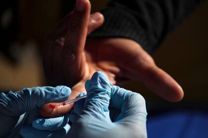 Un trabajador de la salud realiza una prueba rápida de COVID-19 en un sitio de prueba dirigido a recolectores de basura, barrenderos y vendedores ambulantes, en un centro deportivo en el barrio de La Florida de Santiago, Chile, el miércoles 15 de julio de 2020.