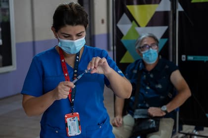 Un trabajador de la salud se prepara para administrar una dosis de la vacuna china CoronaVac a un docente en un centro de vacunación en Santiago de Chile