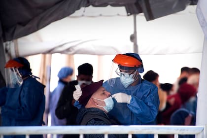Un trabajador de la salud toma el hisopado de un hombre para la prueba de coronavirus