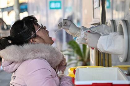 Un trabajador de la salud toma una muestra de hisopo de una mujer para analizar el coronavirus Covid-19 en el distrito de Jing'an en Shanghái el 22 de diciembre de 2022.
