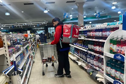 Un trabajador de plataformas de delivery realiza compras en un supermercado.