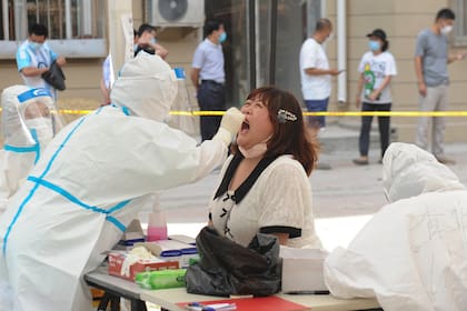 Un trabajador de salud realiza una prueba de coronavirus en un residente en un centro de pruebas improvisado en Dalian, en la provincia de Liaoning, noreste de China, el 28 de julio de 2020