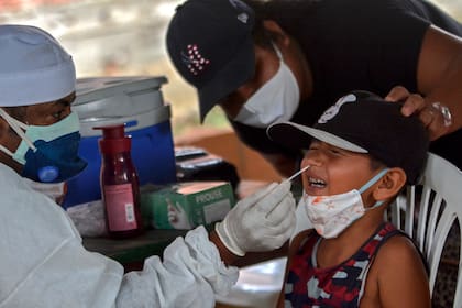 Un trabajador de salud toma una muestra de hisopado de un niño para realizar una prueba de coronavirus en la comunidad ribereña de Bela Vista do Jaraqui, Manaos, estado de Amazonas, Brasil, el 18 de enero de 2021