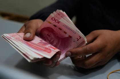 Un trabajador de una casa de cambio cuenta billetes de yuanes chinos