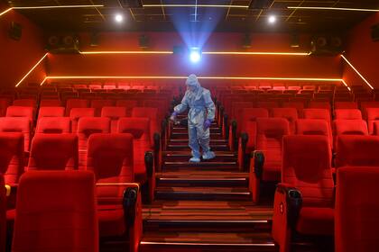 Un trabajador desinfecta una sala de teatro antes de la reapertura programada de las salas de cine el 15 de octubre en Mumbai