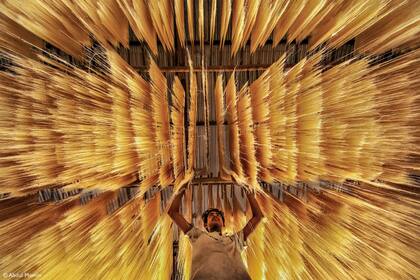 "Un trabajador está inspeccionando (si) los fideos de arroz (se secaron) correctamente o no"