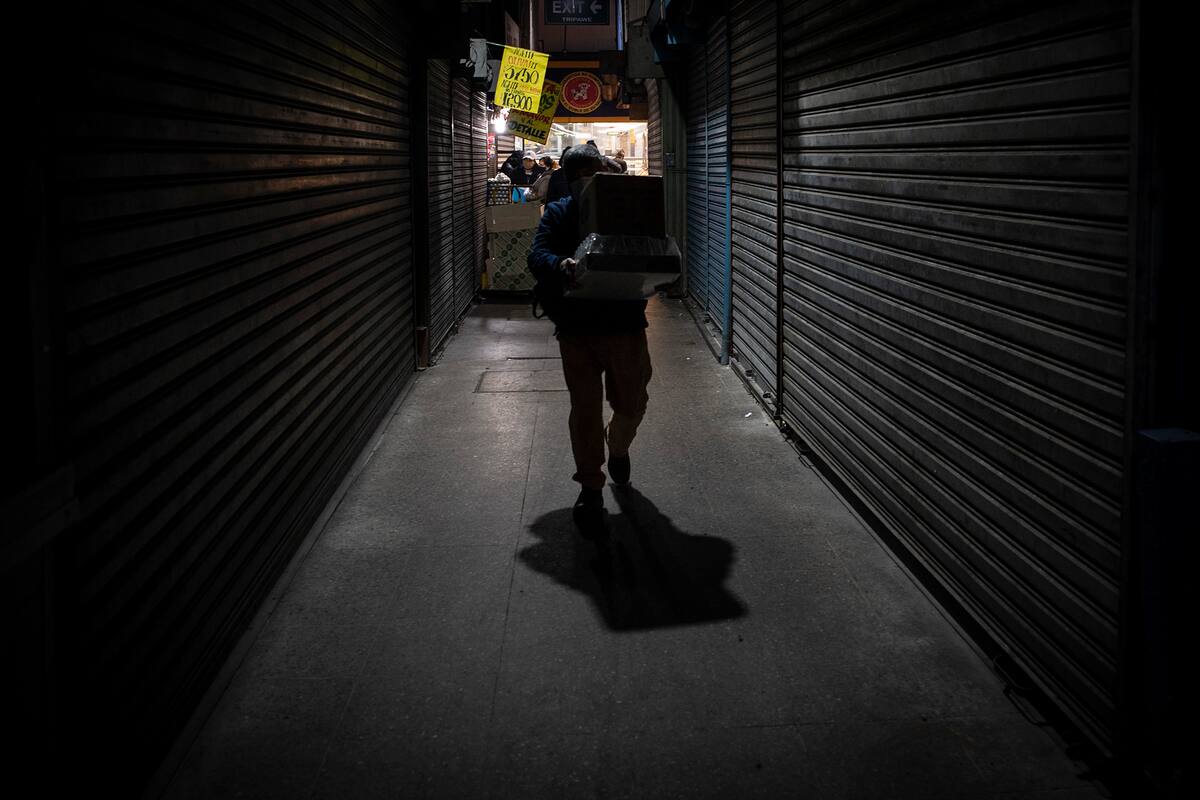 Un trabajador lleva cajas con comida en un mercado popular en Santiago, el 22 de junio de 2020, en medio de la pandemia de coronavirus