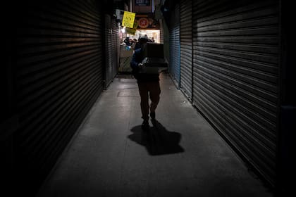 Un trabajador lleva cajas con comida en un mercado popular en Santiago, el 22 de junio de 2020, en medio de la pandemia de coronavirus