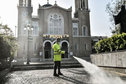Un trabajador municipal desinfecta la explanada frente a la Iglesia Metropolitana de Atenas el 15 de abril de 2020, mientras el país permanece bajo cuarentena para detener la propagación de la pandemia de coronavirus