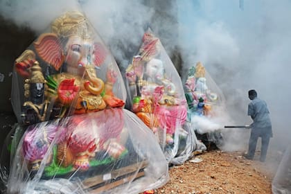 Un trabajador municipal fumiga una colonia de viviendas y estatuas de la deidad hindú con cabeza de elefante Ganesha antes del festival Ganesh Chaturthi en Chennai el 13 de septiembre de 2023.