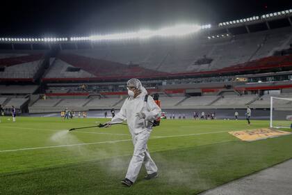 Un trabajador rocía el ambiente del estadio Monumental, antes de un partido de River en la Copa Libertadores