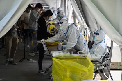 Un trabajador sanitario rocía desinfectante en un lugar de pruebas improvisado en Zhongguancun, en Pekín, el 26 de abril de 2022.