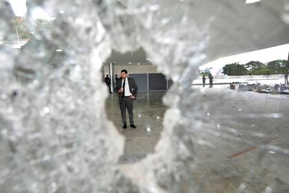 Un trabajador se para al otro lado de una ventana rota en el Palacio de Planalto el día después de que la oficina del presidente fuera asaltada por partidarios del expresidente brasileño Jair Bolsonaro en Brasilia