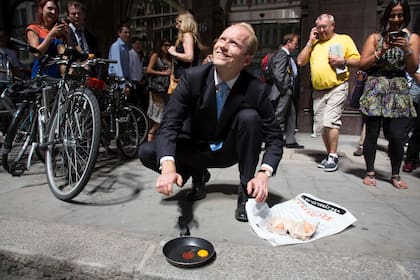 Un transeúnte trata de freír un huevo frente al "Walkie Talkie" en la ciudad de Londres después de que la luz del sol reflejada desde el edificio derritiera un auto