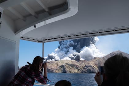 Un turista saca una foto desde el barco de excursión de la erupción del volcán en la Isla Blanca en Nueva Zelanda