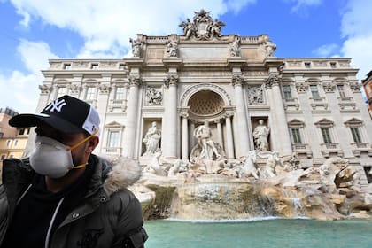 Un turista con barbijo, ante la emblemática Fontana di Trevi, en Roma