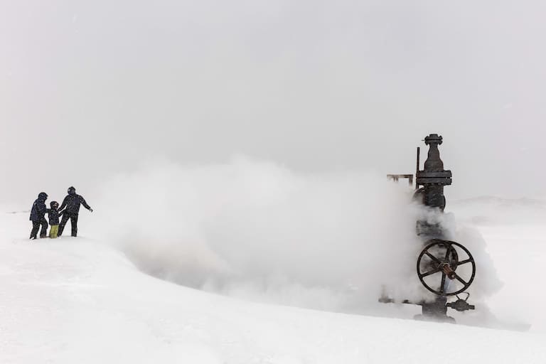 Un vapoducto de la usina geotérmica expulsa vapor con mucha presión: una nube caliente sobre la nieve.