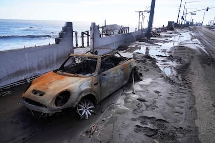 Un vehículo dañado por el fuego es abandonado frente a una propiedad en primera línea de playa tras una tormenta el viernes 14 de febrero de 2025, en Malibú, California. (AP foto/Damian Dovarganes)