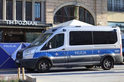 Un vehículo policial permanece estacionado frente a un restaurante en el que dos hombres murieron a balazos en una popular zona turística, el domingo 16 de julio de 2023, en Poznan, Polonia. (AP Foto/KWP Poznan)