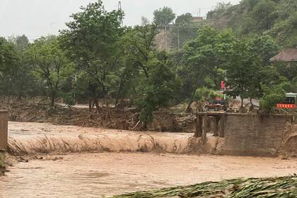 Un vehículo se ve cerca de un puente destruido por las crecidas en un río de Qingyang, en el noroeste de la provincia china de Gansu, el sábado 16 de julio de 2022. (Chinatopix Via AP)