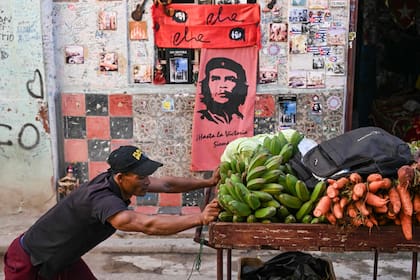 Un vendedor ambulante pasa con su carro junto a un local de souvenirs con la icónica imagen del Che Guevara, en La Habana