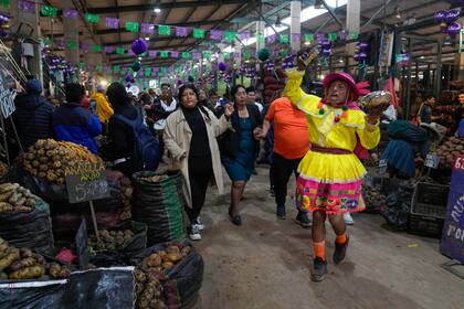 Un vendedor del mercado actúa, disfrazado, cerca de un puesto de venta de papas, celebrando el Día Internacional de la Papa, en las afueras de un mercado en Lima, Perú, el jueves 30 de mayo de 2024. (AP Foto/Martín Mejía)