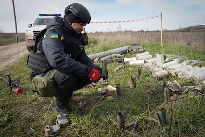 Un zapador del Servicio de Emergencia del Estado ucraniano recoge restos de obuses, granadas y otros artefactos en el sitio de desminado cerca de la aldea de Kamenka, provincia de Járkov, Ucrania, martes 11 de bril de 2023. (AP Foto/Andrii Marienko)