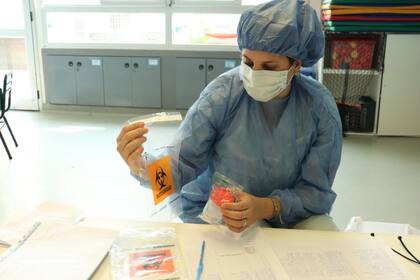 Una agente del plan Detectar en los barrios porteños prepara la muestra de saliva en un frasco estéril para enviarla al laboratorio del Hospital Múñiz