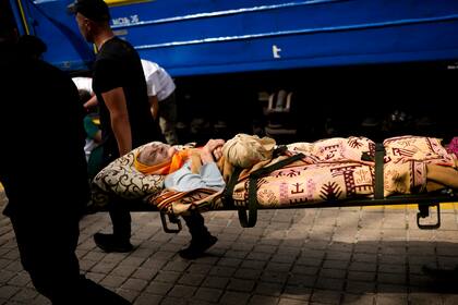 Una anciana es transportada en camilla para abordar un tren de evacuación médica operado por Médicos sin Fronteras en la estación de tren de Pokrovsk, en el este de Ucrania, el domingo 29 de mayo de 2022. (AP Foto/Francisco Seco)