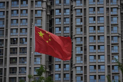 Una bandera nacional china ondea junto a un edificio residencial en Beijing, el lunes 16 de junio de 2025. (AP Foto/Andy Wong)