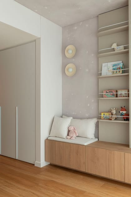 Una biblioteca a medida se acompaña con un mueble empotrado que suma guardado. Empapelado (Mercedes Costal)