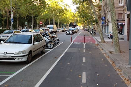Una bicisenda de Barcelona: ancha, nivelada y con una franja de seguridad respecto de los automóviles y motos estacionados