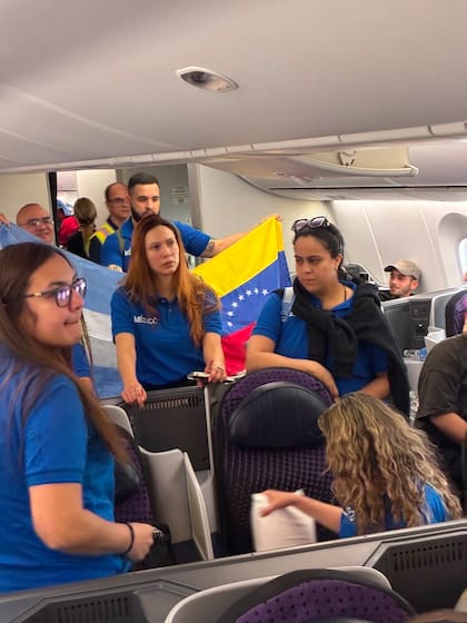 Una brigada de médicos venezolanos residentes en Argentina despliega una bandera de Venezuela junto a una bandera de Argentina en la cabina del avión