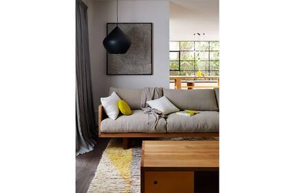 Una caja de madera sostiene almohadones bien mullidos en este living actual