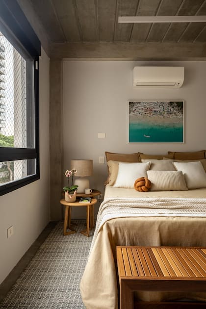 Una cama llena de almohadones se opone a la dureza del cielorraso de hormigón.