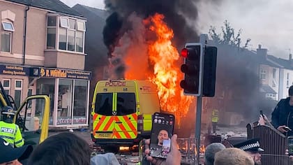 Una camioneta de la policía arde mientras una multitud choca con la policía el martes 30 de julio de 2024 en Southport, en el noroeste de Inglaterra, cerca de donde tres niñas murieron apuñaladas en una clase de danza el día anterior. La violencia estalló poco después de una vigilia pacífica a la que asistieron cientos de personas en el centro de Southport en gesto de duelo por las víctimas. (Richard McCarthy/PA via AP)