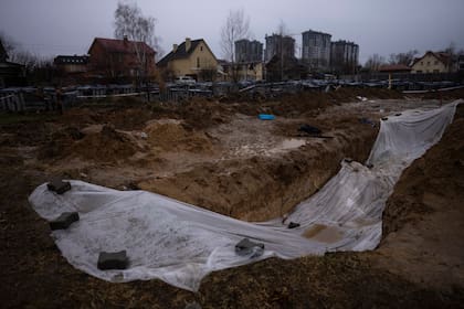 Una capa de plástico cubre una fosa común donde se encuentran enterrados civiles muertos durante la guerra contra Rusia, el domingo 10 de abril de 2022, en Kiev, Ucrania. (AP Foto/Rodrigo Abd)