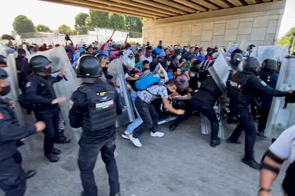 Una caravana de migrantes, la mayoría de Centroamérica, atraviesa por la fuerza una barricada de la policía mexicana en Tapachula, México, el sábado 23 de octubre de 2021. (AP Foto/ Edgar H. Clemente)