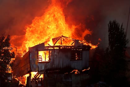 Una casa arde tras la propagación de incendios forestales