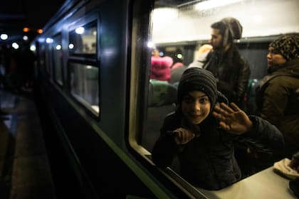 Una chica ucraniana saluda desde el tren que la llevó como refugiada a Bucarest, en la vecina Rumania