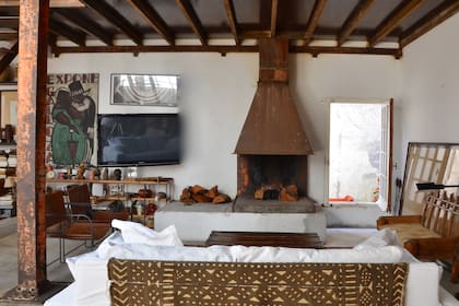 Una chimenea de hierro le da clima al estar de la casa esteña del arquitecto Álvaro Farina. Además, está a tono con las vigas, columnas y con las sillas de hierro y cuero que el arquitecto presentó en la bienal de Saint-Étienne.