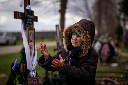 Una ciudadana ucraniana llora en la tumba de su hijo en Bucha