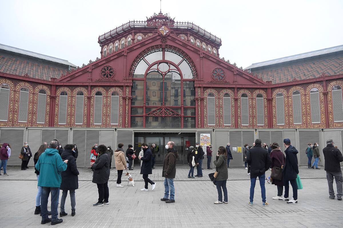 Una cola de votantes fuera del mercado de Sant Antoni, que se utiliza como colegio electoral en Barcelona