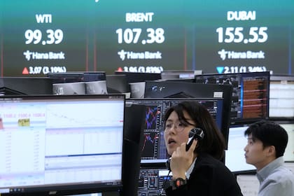 Una corredora de divisas trabaja junto a una pantalla en la que se muestran los precios internacionales del petróleo en la sala de operaciones de la sede central del Hana Bank en Seúl, Corea del Sur, el jueves 19 de marzo de 2026. (AP Foto/Ahn Young-joon)