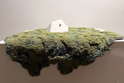 Una de las casas hundiéndose en el paisaje hilado de verdes, azules y amarillos.