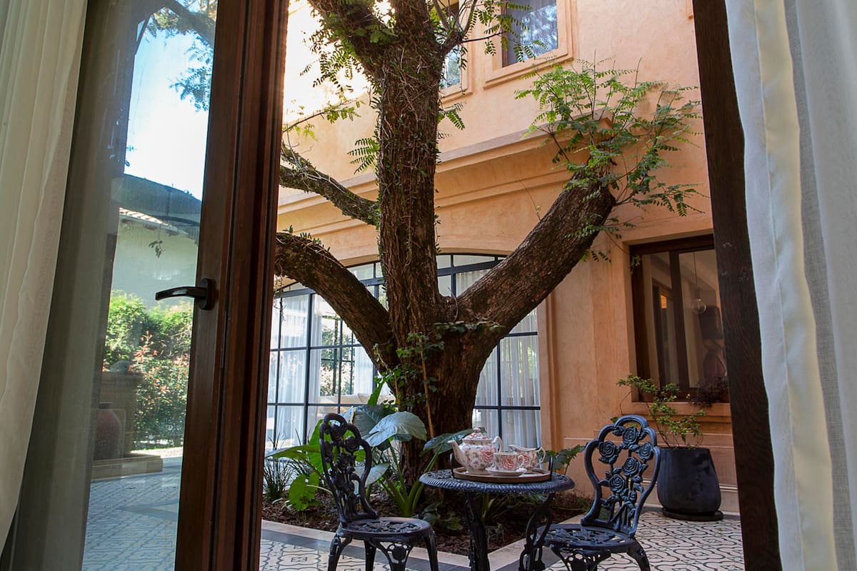 Una de las galerías se creó íntegramente respetando un árbol. Con sus pisos calcáreos y el juego de jardín de estilo vintage, es uno de los rincones preferidos de la casa. Los mismos calcáreos rodean la galería y la pileta, y generan un contraste con los pisos del interior de la casa, más neutro.