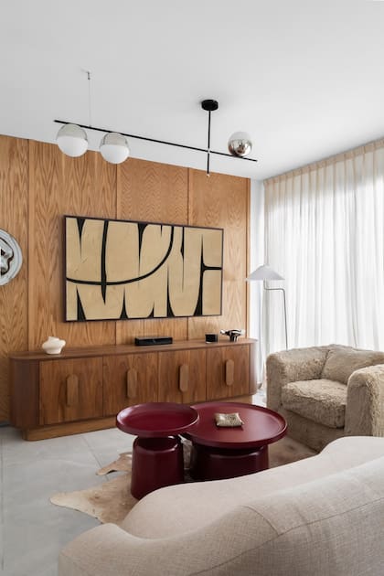 Una de las grandes apuestas fue revestir la pared del living en roble americano y acompañarla de una consola en nogal. "Le gustaba esta idea de jugar con distintas maderas"