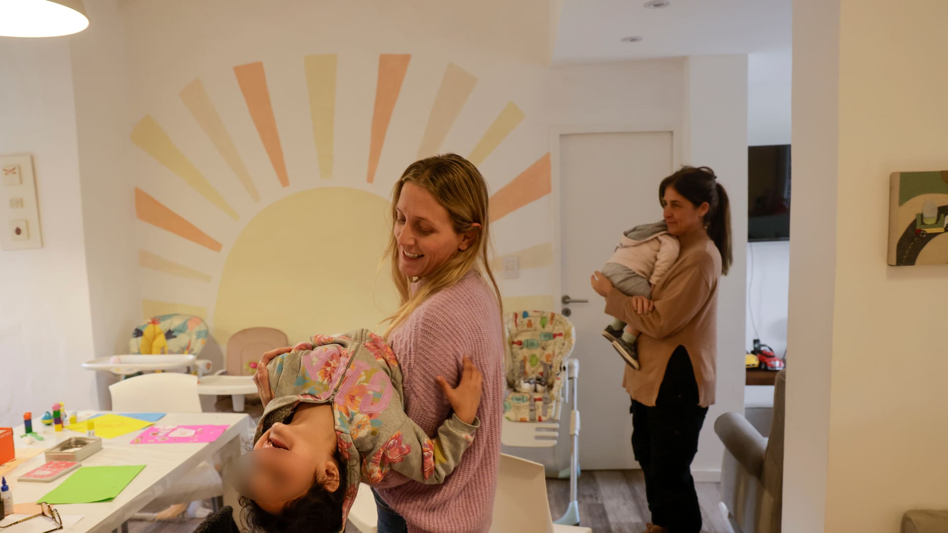 Una de las voluntarias carga en sus brazos a uno los primeros 10 niños que llegaron al hogar